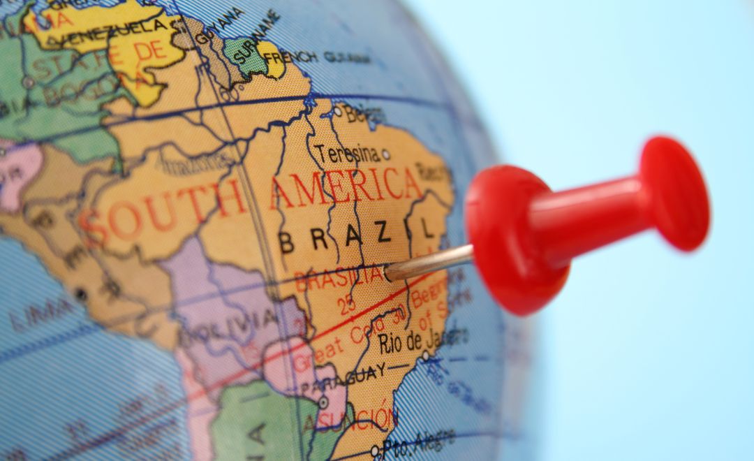 A globe with a red pushpin stuck in Brazil
