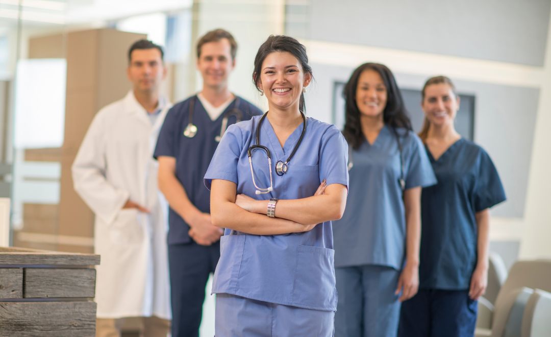 Five healthcare professionals standing and smiling at the camera